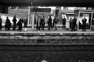 Passagers sur un quai, silhouettes indistinctes, comme des signes d’écriture sur une ligne.